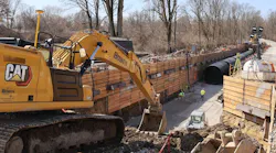 Excavator in trench with pipe