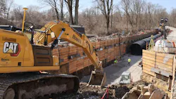 Excavator in trench with pipe