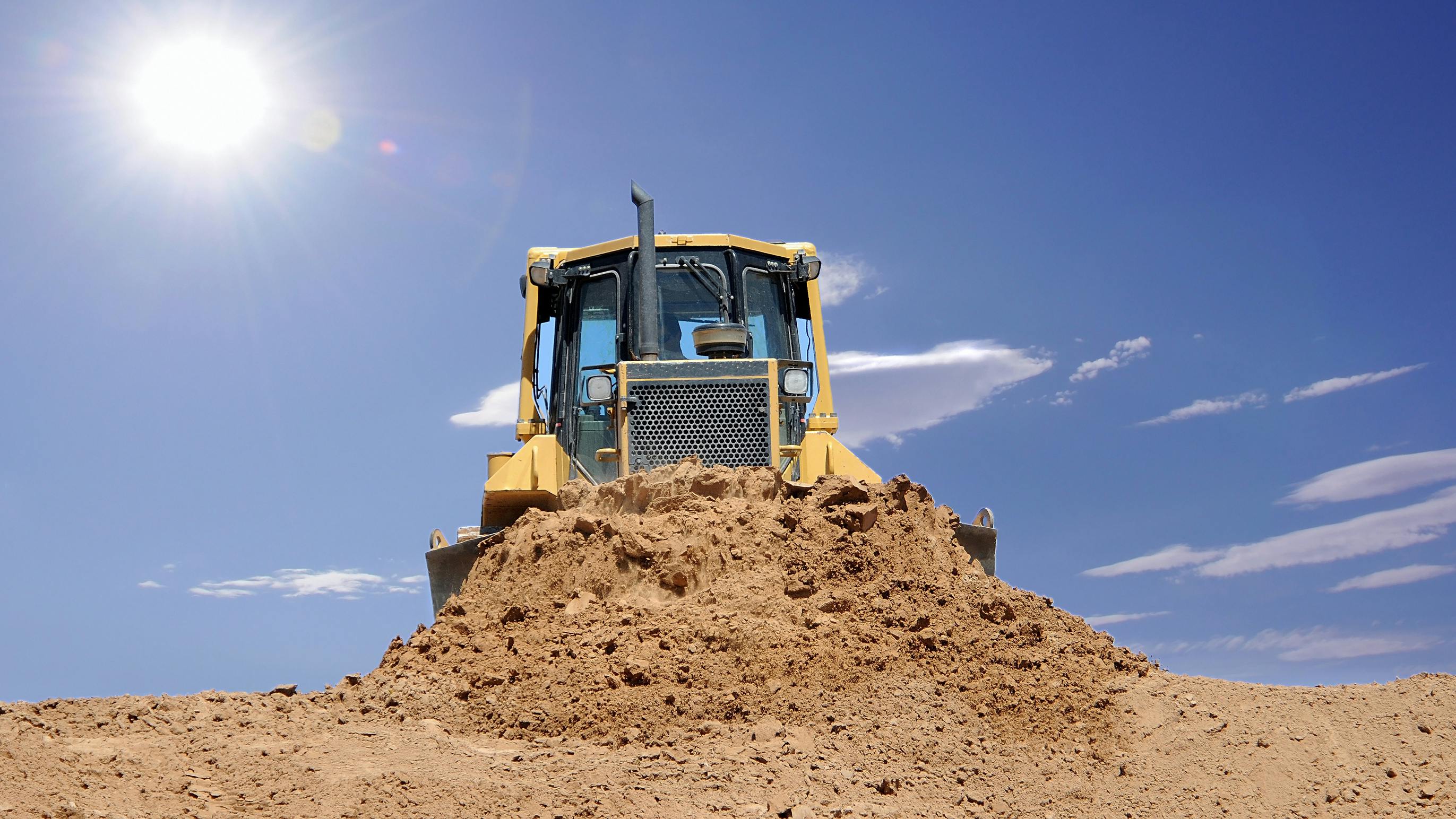 dirt dozer with the sun in the background