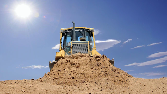dirt dozer with the sun in the background