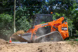 Develon DTL26 compact track loader holding dirt in a bucket.