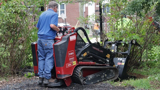 ARA Toro Community Impact Event in Baltimore. A man operates a Toro Dingo, cleaning up brush.