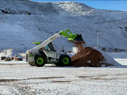JCB hydrogen telehandler in a snowy quarry, dumping dirt.