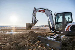 Bobcat E88 compact excavator digging in a snowy field.