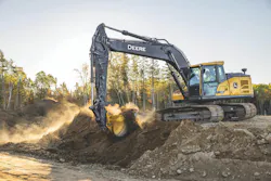 John Deere excavator digging dirt in the sun.