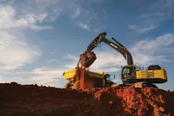 John Deere 510 P-Tier excavator dumping dirt into a truck.