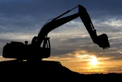 Loader excavator over sunset. Silhouette of Excavator loader at construction site with raised bucket over sunset