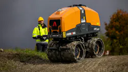 Ammann remote-control trench roller with an operator in the background.
