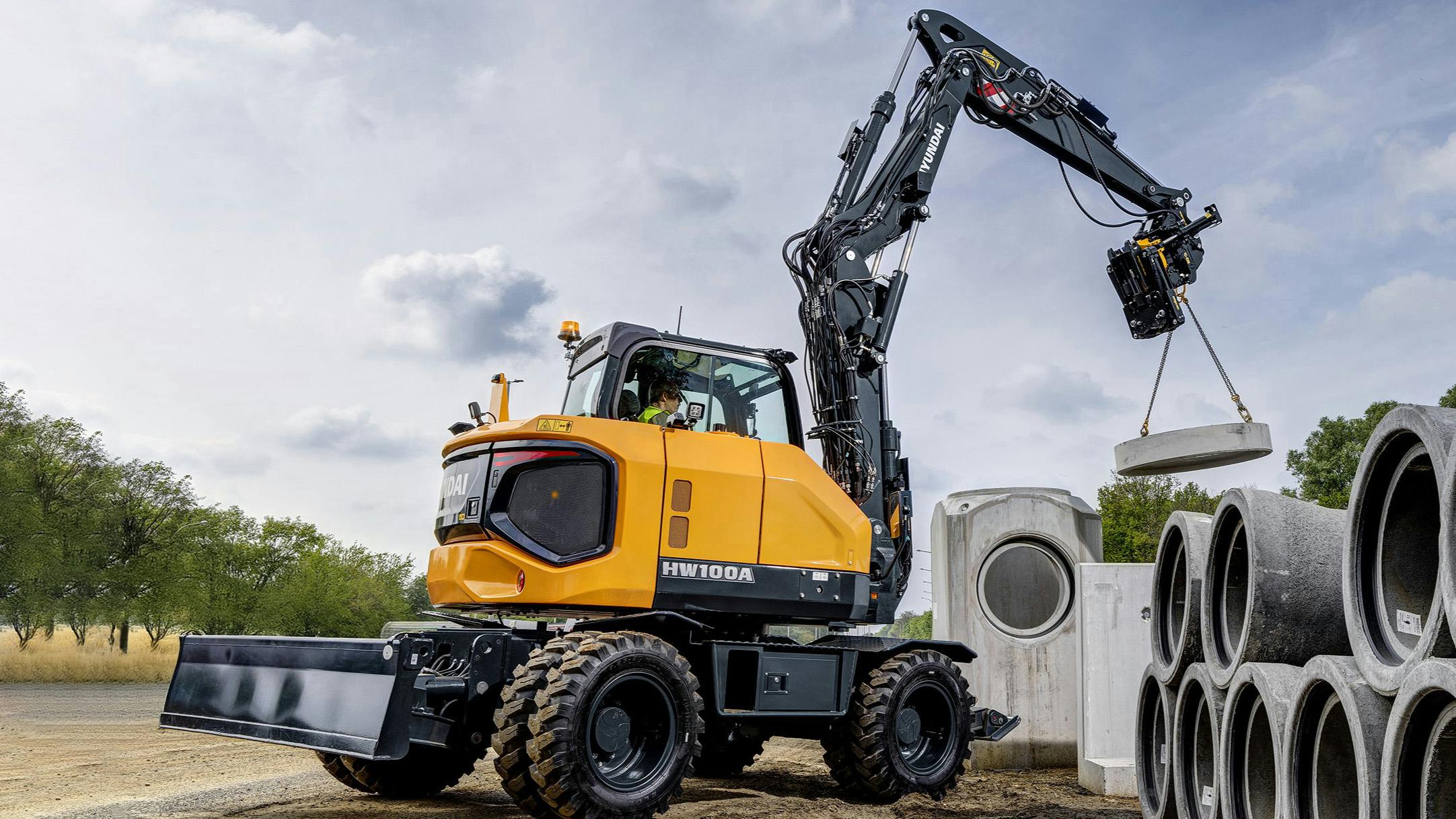 Hyundai HW100A wheeled excavator lifting pipes and culverts.