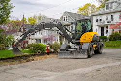 Mecalac MWR1 wheeled excavator, reaching into a yard to dig.