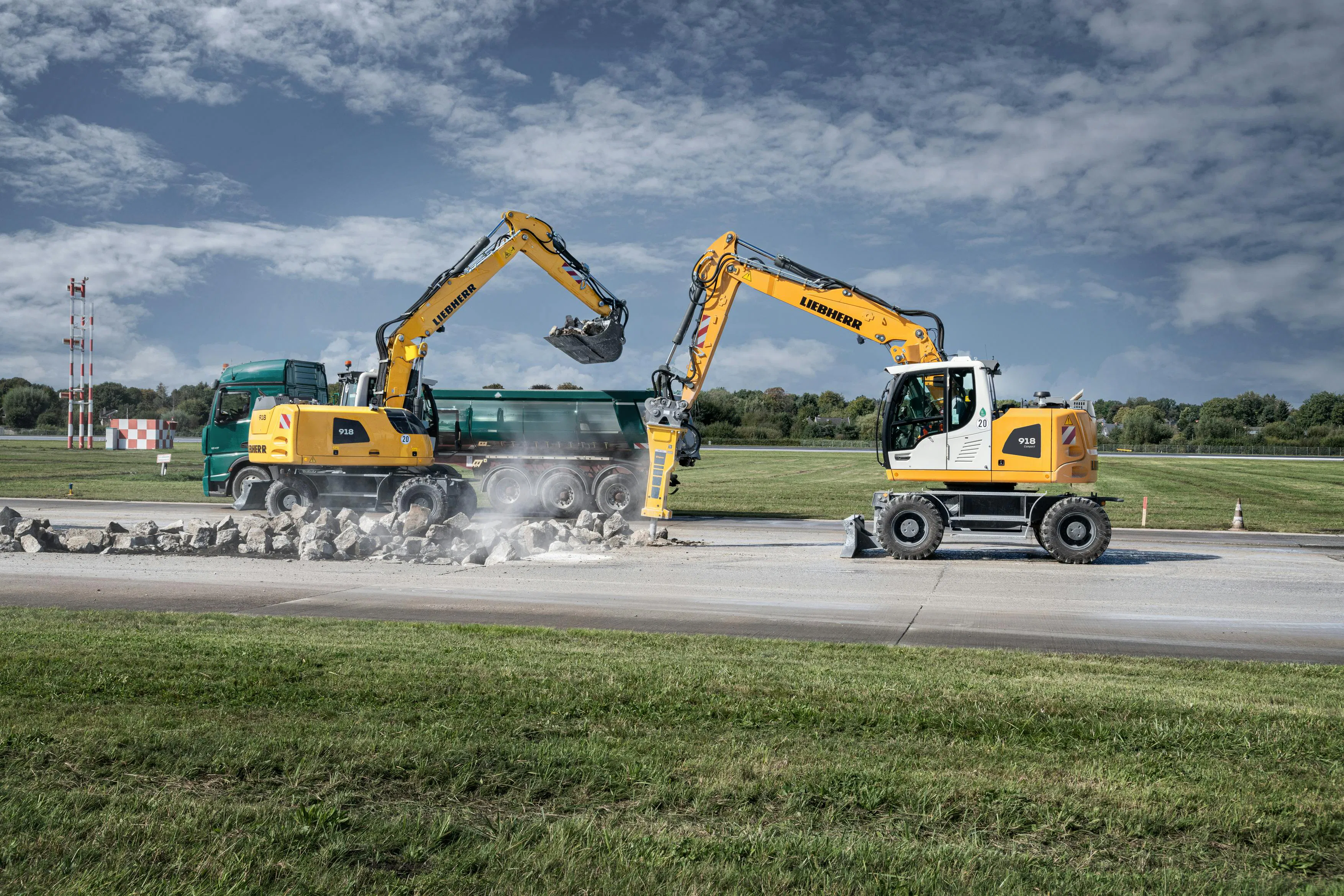 Liebherr 918 wheeled excavators. One is digging, and one is using a hammer attachment.