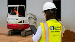 United Rentals employee working a tablet, looking at a mini excavator.