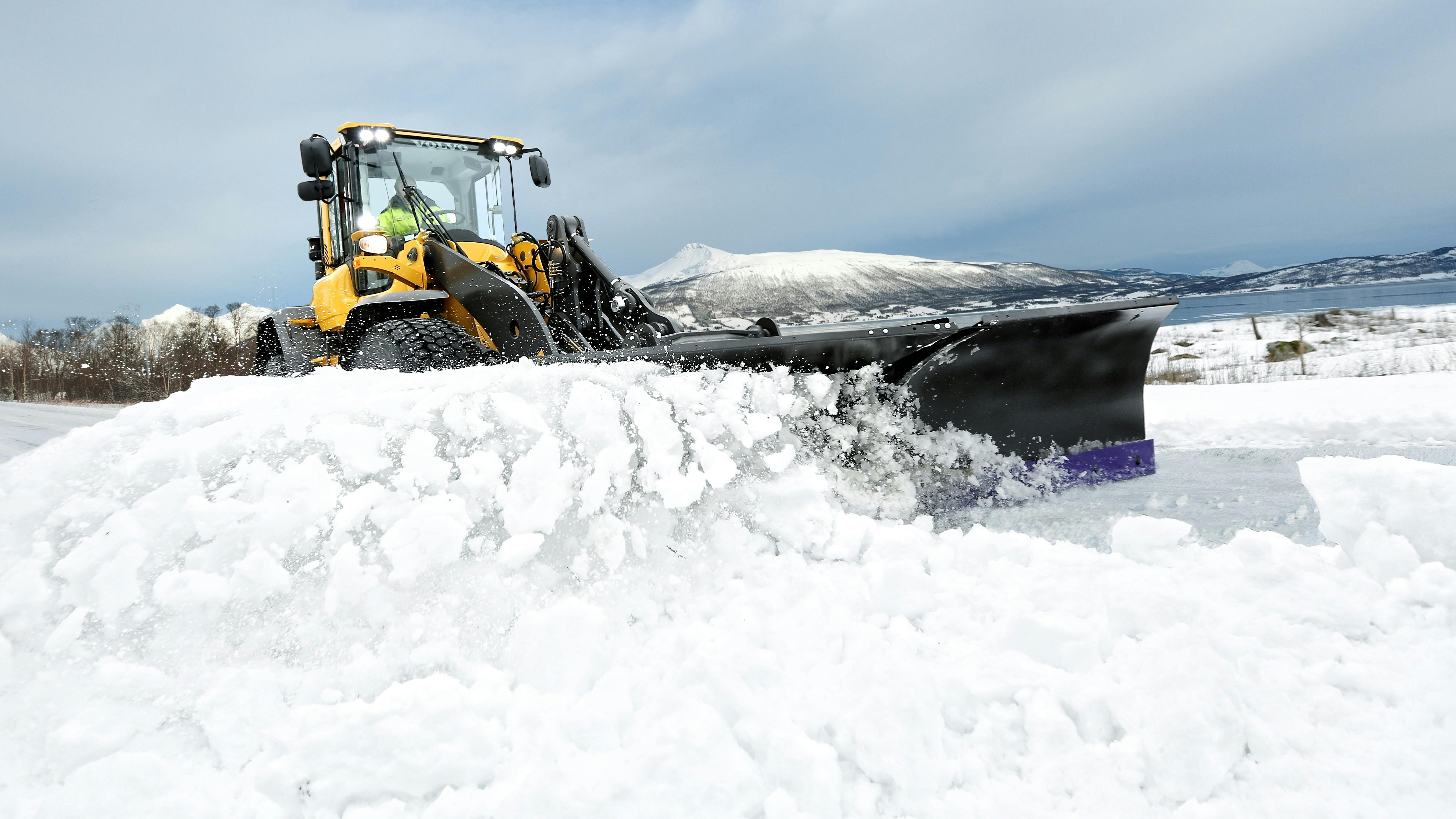 A Volvo mid-size wheel loader plowing snow.
