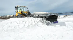 A Volvo mid-size wheel loader plowing snow.