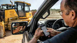 John Deere Operations Center. Man checks his phone while looking at a John Deere dozer.