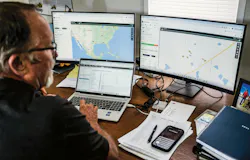 John Deere Operations center. Man in front of multiple computer screens, analyzing machine patterns.