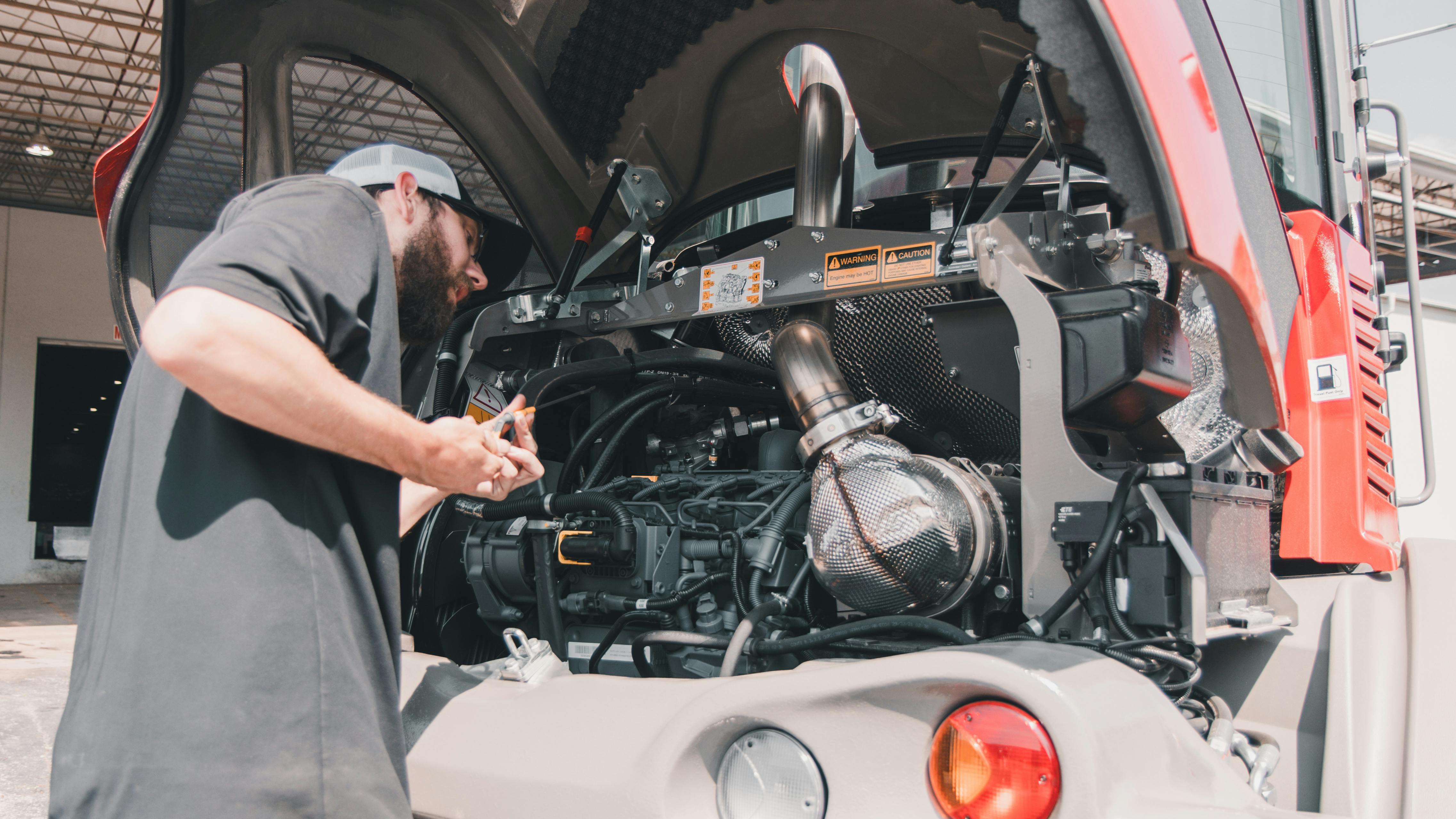 Mechanic checking the oil on a Takeuchi compact wheel loader.