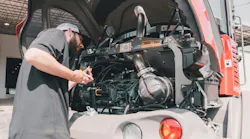 Mechanic checking the oil on a Takeuchi compact wheel loader.