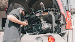 Mechanic checking the oil on a Takeuchi compact wheel loader.