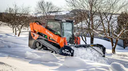 Kubota SVL97-3 compact track loader with a snow pusher attachment, cleaning up snow.