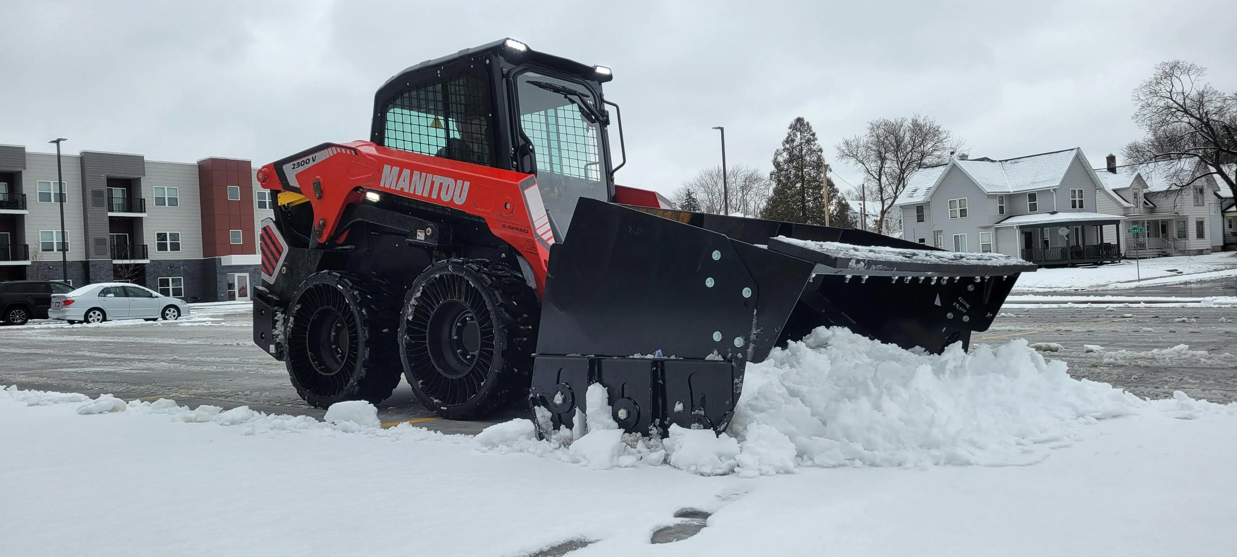 Manitou skid steer using a snow pusher to clear snow.