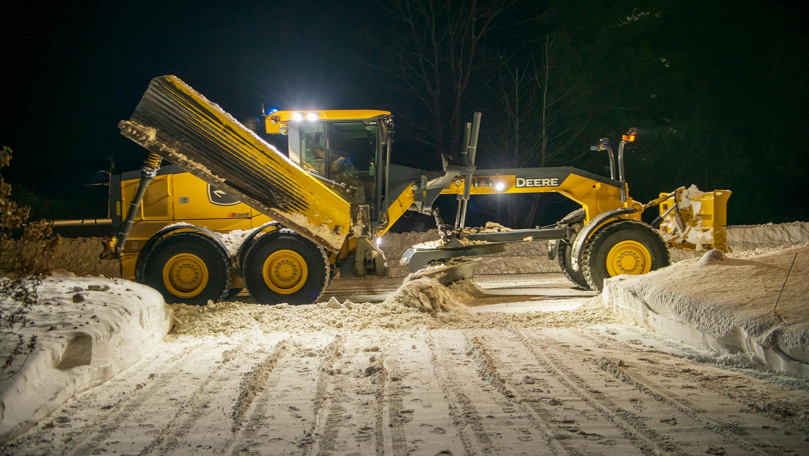 John Deere grader plowing snow at night