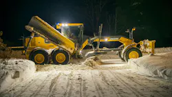 John Deere grader plowing snow at night