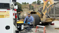 construction equipment mechanic working with grease and filter. Maintenance.