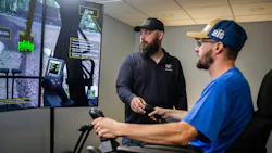 Caterpillar Next Gen Excavator Utilities Package. Man directs an operator on a simulator.