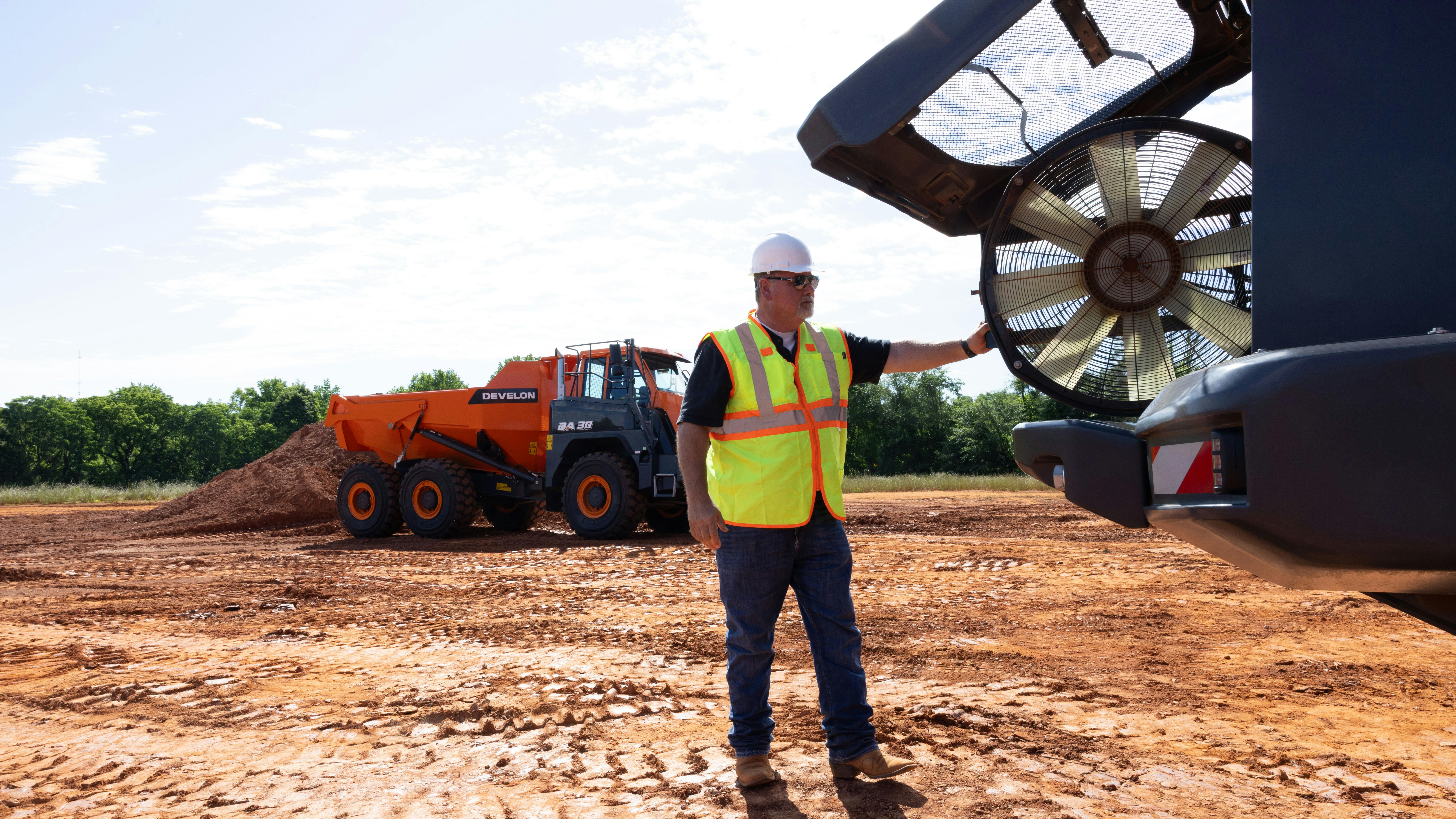 A man checks the fan on a Develon articulated dump truck.