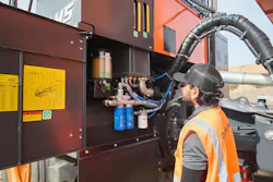 A mechanic checks filters and fluids on a Develon excavator.