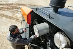 A mechanic pulls out an air filter on a Develon ADT.