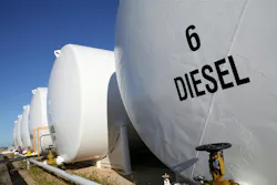 A row of diesel fuel tanks is contrasted with the blue sky.