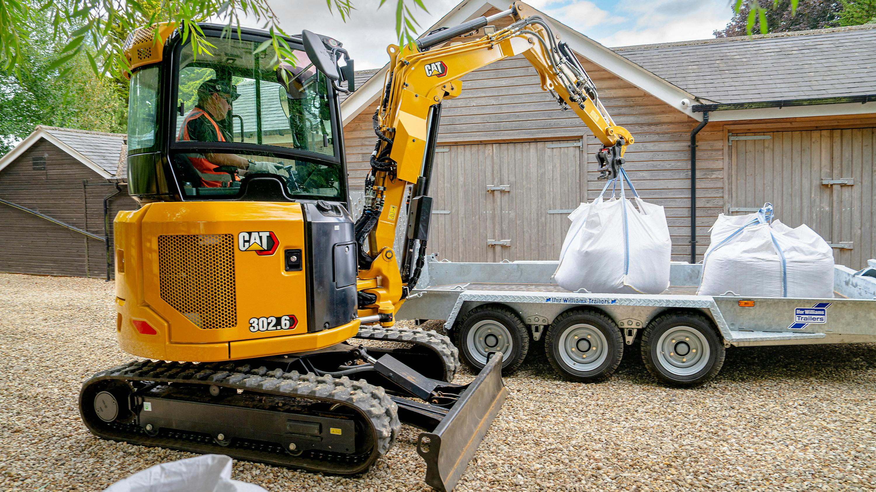 Caterpillar 302.6 mini excavator lifting bags onto a trailer.