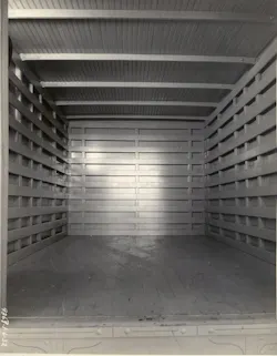 This archival view looks inside an Omaha Standard enclosed truck body, showing its wood floor, slatted interior walls, and roof supports.