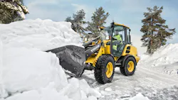 A Volvo compact wheel loader digging into a pile of snow.