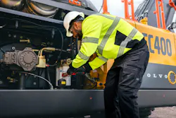 A mechanic changes the oil filter on a Volvo Construction Equipment excavator.