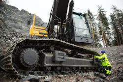 A technician services the undercarriage of a Volvo Construction Equipment excavator.