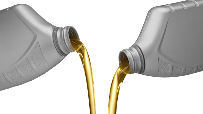Two oil bottles are being poured on a white background.