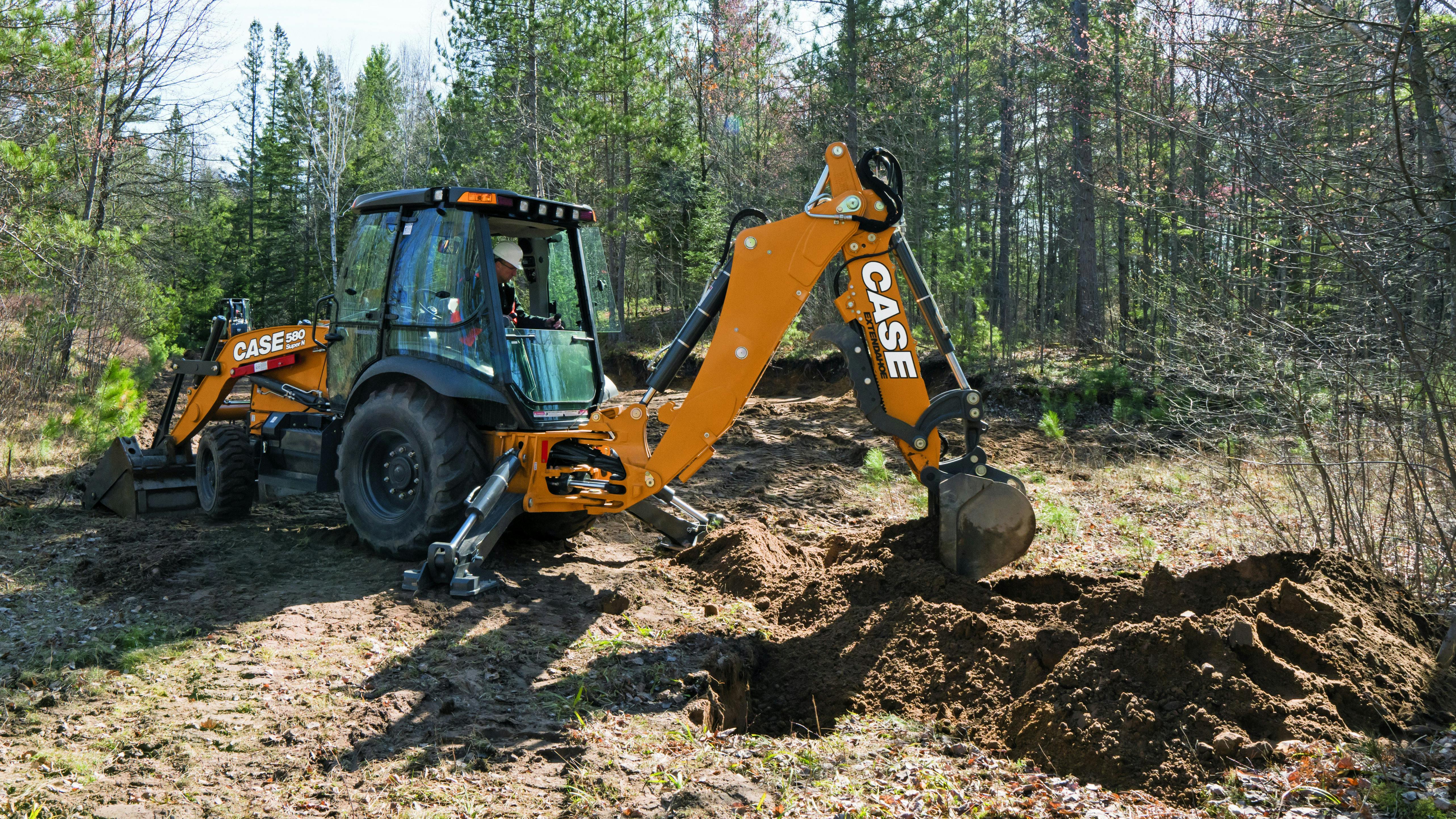 Case 580 Super N backhoe loader digging in a forest.