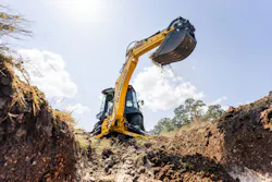 A New Holland B95D loader backhoe digging dirt in the sun.