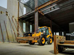 A JCB 4cx Pro backhoe loader carries steel on a pallet fork.