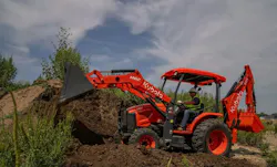 A Kubota M62 tractor loader backhoe dumping dirt into a pile.