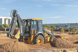 A John Deere 310 P-Tier backhoe loader pushing dirt on a jobsite.