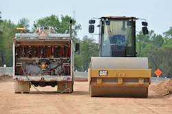 A fluids service truck works on a Cat compaction roller in the field.