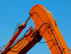 A closeup of an excavator boom and its hydraulic lines