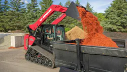 A Yanmar compact track load dumps read mulch into a bin.