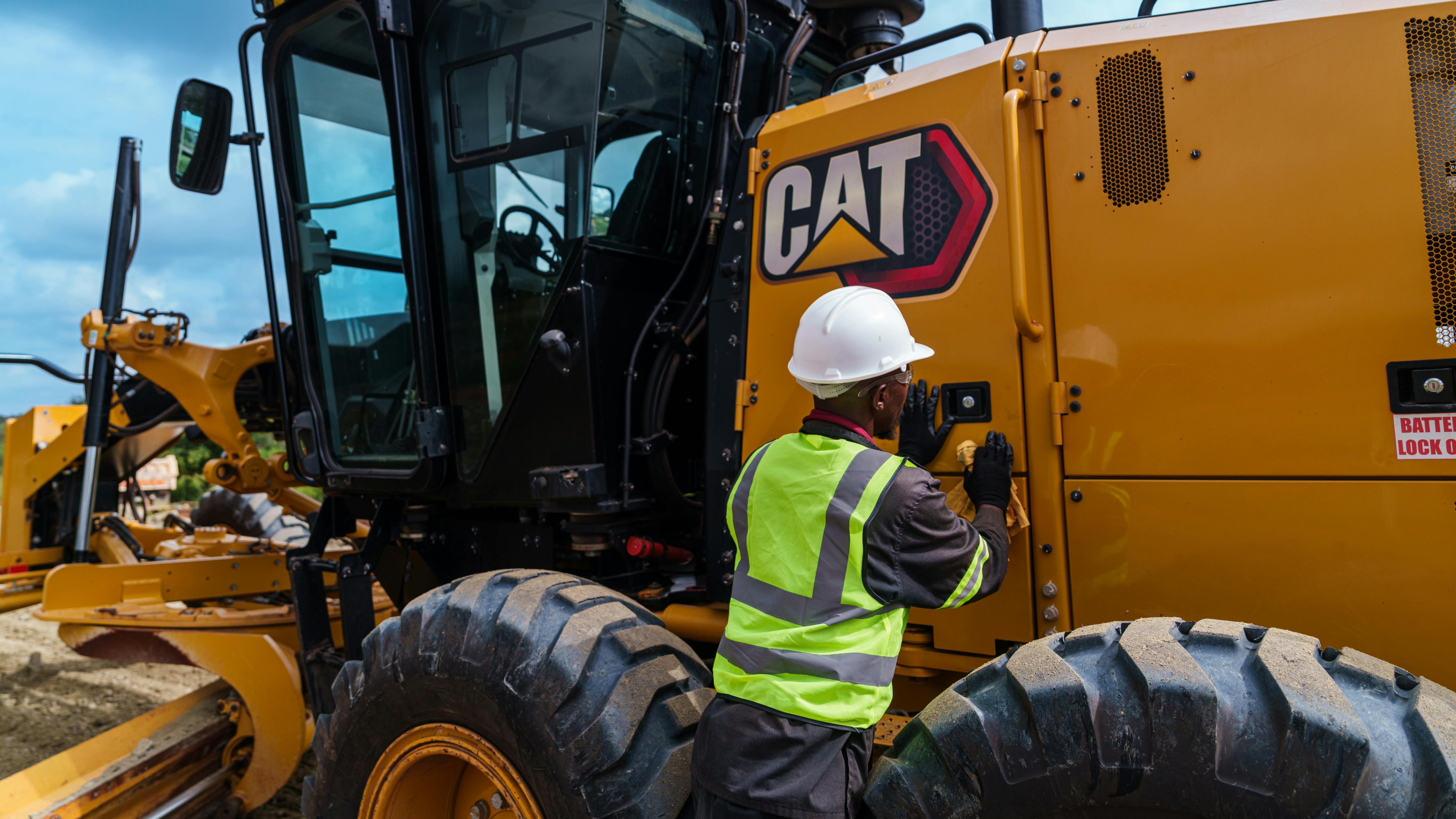 A mechanic looks to inspect a Caterpillar 140 motor grader.