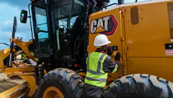 A mechanic looks to inspect a Caterpillar 140 motor grader.