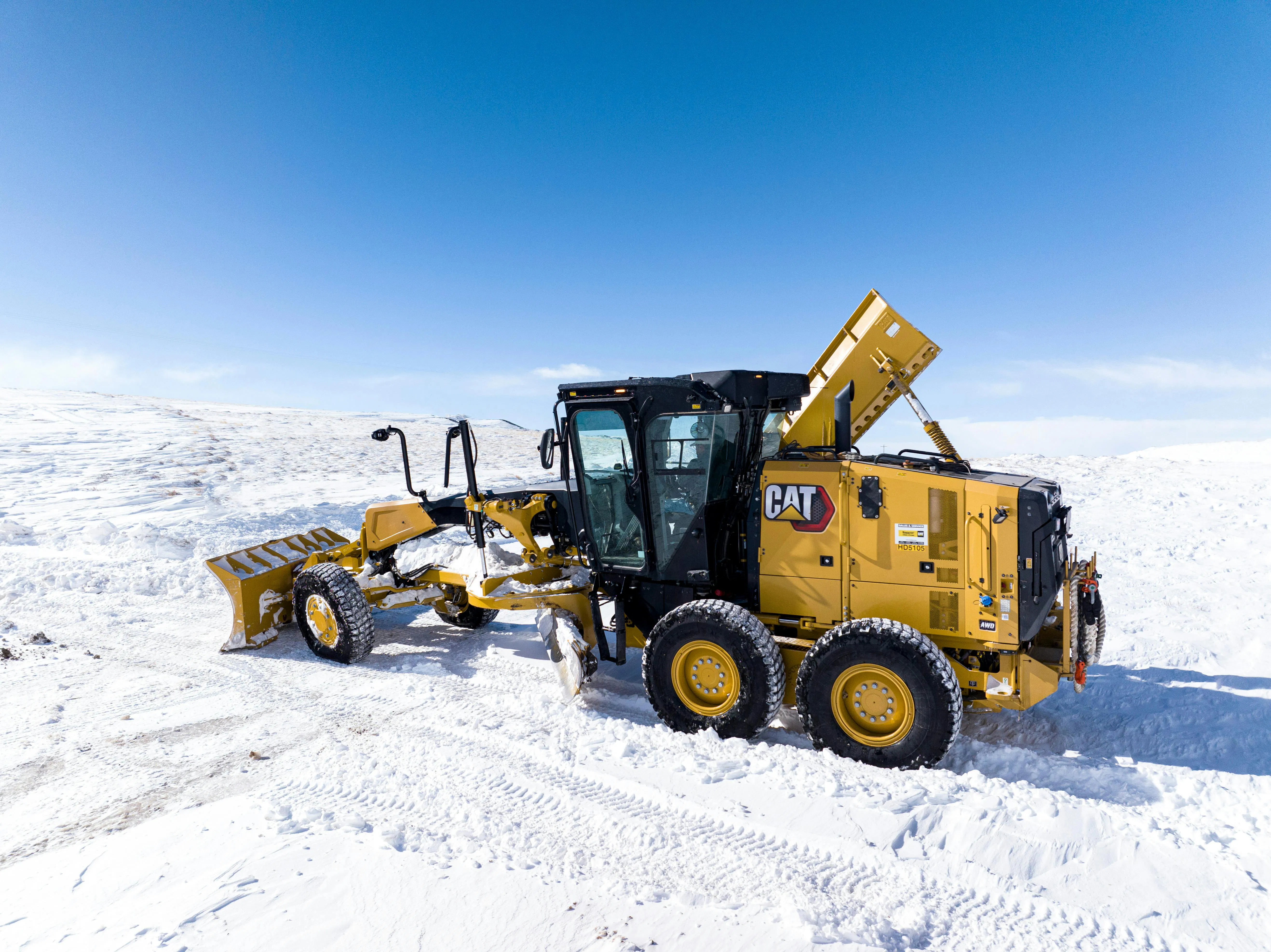 A Caterpillar 140 Next Gen wheel loader working in the snow